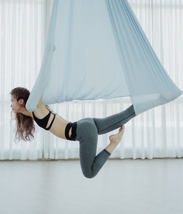 Woman practicing a calm yoga pose in a studio with lavender colors.